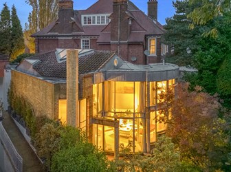 General view of a house with floor-to-ceiling windows lit at twilight